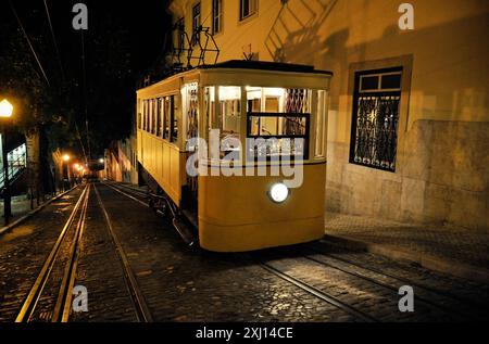 Glória Seilbahn bei Nacht. Elevador da Glória - oberes Ende der Eisenbahnstrecke. Alte gelbe Seilbahn mit hellem Scheinwerfer in der Mitte. Stockfoto