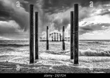 Ein Bild von Brightons West Pier vor einem Hintergrund dunkler, brütender Sturmwolken, alle in einem starken Schwarz-weiß-Ton Stockfoto