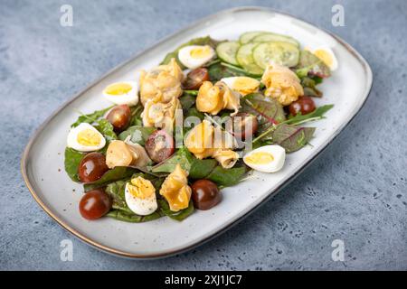 Warmer Salat mit Raps (Schnecken), Tomaten, Gurken, Blattgemüse, Wachteleiern und Olivenöl. Traditioneller Salat mit Meeresfrüchten. Nahaufnahme, selektiver Fokus. Stockfoto