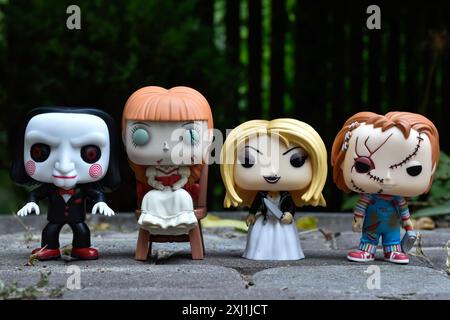 Funko Pop Actionfiguren von bösen Puppen aus Horrorfilmen. Billy, die Puppe, Annabelle, Tiffany und Chucky. Dunkler Hof, Schatten, stimmungsvolles Grün. Stockfoto