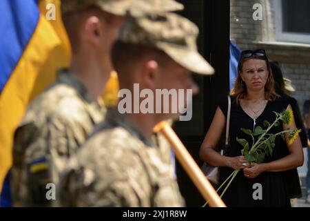 Kiew, Ukraine. Juli 2024. Eine Frau steht mit Blumen, die während der Beerdigung des Befehlshabers des OUN-Freiwilligenbataillons Mykola Kokhanivskyi in Kiew gesehen wurden. Beerdigung des Bataillonskommandeurs der Organisation der Ukrainischen Nationalisten (OUN) Mykola Kokhan?vsky bei Pseudo Bureviy. Am 10. Juni 2024 wurde das Schicksal von seinem Tod in Charkiwski in der Nähe von Wowchansk bekannt. Quelle: SOPA Images Limited/Alamy Live News Stockfoto