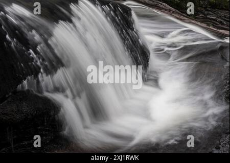 Eine Nahaufnahme eines Wasserfalls in Norwegen, aufgenommen mit einer Langzeitbelichtung. Das Wasser kaskadiert schwarze Felsformationen hinunter und erzeugt einen glatten, seidigen Effekt Stockfoto