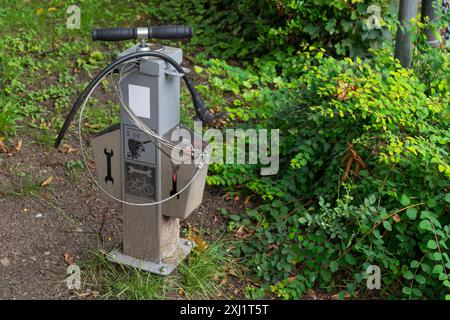 Eine öffentliche Fahrradreparaturstation steht in einer Parklandschaft, umgeben von üppigem Grün. Nahaufnahme. Stockfoto