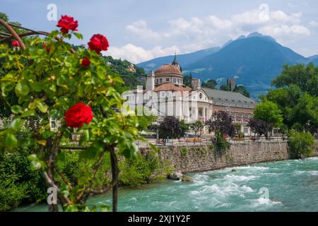 Meran, Südtirol, Italien - Kurhaus am Fluss Passer, an der Passerpromenade in der Altstadt. Vorne Rote Rosen auf der Thermenbrücke. Meran Süddtirol Italien *** Meran, Südtirol, Italien Kurhaus an der Passer-Promenade in der Altstadt Rote Rosen vor der Thermalbrücke Meran Südtirol Italien Stockfoto