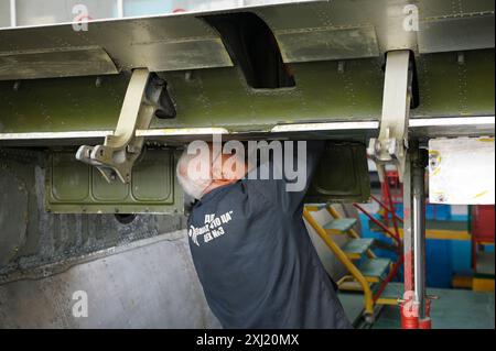 Flugzeugüberholung. Elektriker, der neue elektrische Leitungen in einer Karosserieebene installiert Stockfoto