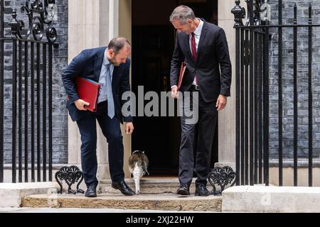 London, Großbritannien. Juli 2024. Ian Murray Abgeordneter (l), Secretary of State for Scotland, versucht Larry die Katze zu streicheln, als er 10 Downing Street mit Peter Kyle Abgeordneter (r), Secretary of State for Science, Innovation and Technology, nach einer Kabinettssitzung verlässt. Der britische Premierminister Sir Keir Starmer hat geraten, dass sein neues Kabinett mit dem Schwerpunkt auf der Lieferung „auf den Boden gehen“ muss. Quelle: Mark Kerrison/Alamy Live News Stockfoto