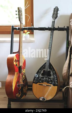 Ein fesselndes Bild mit einer Akustikgitarre und einem Bouzouki auf einem Gitarrenständer. Diese Szene zeigt die Harmonie zwischen diesen beiden Saiten Stockfoto