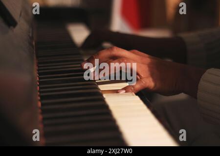 Ein fesselndes Bild der Hände eines schwarzen Mannes, das ein altes Honky Tonk Klavier spielt, aufgenommen mit einer großen Blende. Diese Szene verkörpert Kreativität und Inspiration Stockfoto