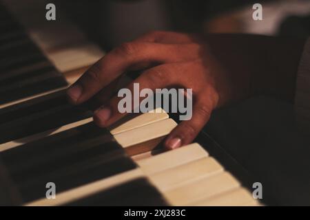 Ein fesselndes Bild der Hände eines schwarzen Mannes, das ein altes Honky Tonk Klavier spielt, aufgenommen mit einer großen Blende. Diese Szene verkörpert Kreativität und Inspiration Stockfoto