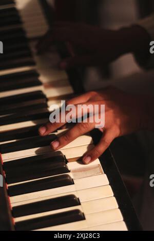 Ein fesselndes Bild der Hände eines schwarzen Mannes, das ein altes Honky Tonk Klavier spielt, aufgenommen mit einer großen Blende. Diese Szene verkörpert Kreativität und Inspiration Stockfoto