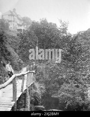 Ein hölzerner Fußweg in Groudle Glen mit dem Hotel auf einem höheren Boden, Isle of man. Dieses Foto stammt von einem edwardianischen Original, um 1910. Das Original war Teil eines Albums von 150 Albumenfotos von unterschiedlicher Qualität, von denen ich viele fotografiert habe. Die Sammlung enthielt Bilder vor allem von der Isle of man und der englischen Grafschaft Devonshire. Anmerkungen waren im Album enthalten, aber leider gab es keine genauen Daten. Die Originalfotos waren durchschnittlich 6 x 4 ½ Zoll. Stockfoto