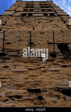 Drahtnetze schützen heute die Öffentlichkeit vor Bruchstücken von schlecht verwittertem Mauerwerk, das aus dem viel reparierten campanile stammt, das 1330 zur romanischen Pieve di Santa Maria in Arezzo, Toskana, Italien hinzugefügt wurde. Der campanile ist von seinen geplünderten Öffnungen als „delle cento buche“ (der hundert Löcher) bekannt. Stockfoto