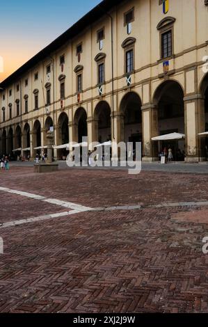 Palazzo delle Logge auf der Piazza Grande in Arezzo, Toskana, Italien. Der lange Portikus, die Loggia oder die Galerie dieses Renaissance-Palastes, der heute mit Esstischen unter Bögen versehen ist, wurde von Giorgio Vasari (1511–1574) in seinen Entwurf für das Gebäude einbezogen. Stockfoto