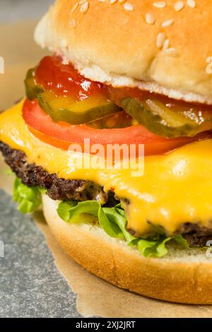 Fast Food Cheeseburger und Pommes Frites mit Salat Tomaten und Gurken Stockfoto