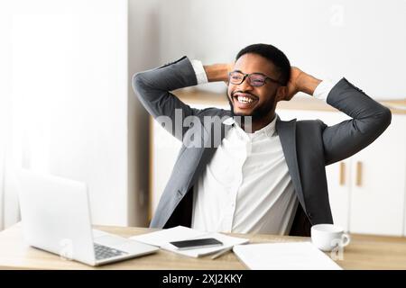 Junge afrikanische amerikanische Geschäftsmann Entspannung am Arbeitsplatz in modernen Büro Stockfoto
