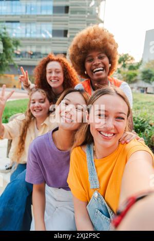 Vertikal. Gruppe von nur jungen Frauen mit multirassischen Rassen, die ein Selfie mit einem Smartphone machen, um es in sozialen Medien zu teilen. Mädchen im Teenageralter, die Spaß haben und lächeln, während sie ein Erinnerungsfoto machen, während sie das Wochenende genießen. Hochwertige Fotos Stockfoto