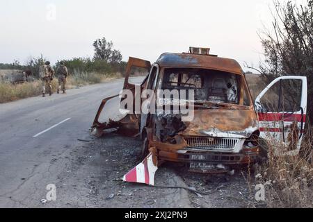 15. Juli 2024, Robotyne, Zaporischschschhia, Ukraine: Ukrainische Soldaten der 65. Separaten Mechanisierten Brigade gehen an dem zerstörten Ambulanzwagen an der Frontlinie bei Robotyne vorbei. Der unnachgiebige Druck der Ukraine, ihre Verbündeten dazu zu bewegen, Ziele innerhalb Russlands mit gespendeten Waffen zu treffen, könnte beginnen zu funktionieren, sagte Präsident Wolodymyr Zelenskij am 15. Juli 2024. Wenn diese Erlaubnis nicht erlaubt wird, wird die Ukraine ihre eigenen Waffen einsetzen, um Russland zu treffen. Viele seiner Verbündeten unter der Führung der USA setzen den Zielen Grenzen, die sie innerhalb Russlands treffen können. Etwas, was Kiew sagt, macht es imposant Stockfoto