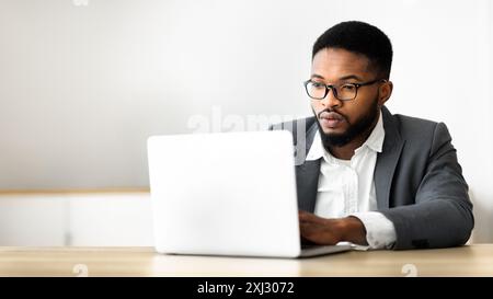 Ernst schwarz Geschäftsmanns, der auf dem Laptop im Büro Stockfoto