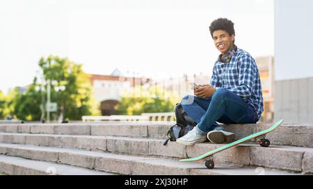 Teenager sitzt auf Urban Treppen mit Skateboard und Telefon Stockfoto