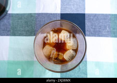 Kalter Americano-Kaffee in einem großen Glas zur Mockup-Verwendung. Kalter Kaffee, der in einem Café auf Eis gegossen wird Stockfoto