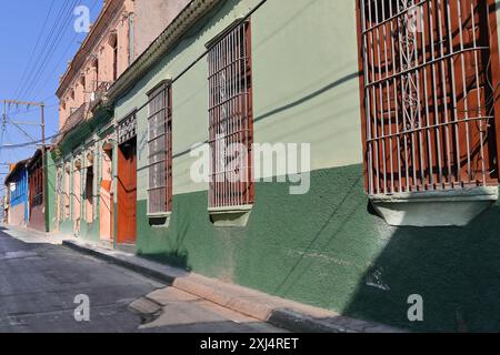 520 eine Reihe einstöckiger Kolonialfassaden flankiert ein zweistöckiges Haus im eklektischen Stil auf der nördlichen Seite der Heredia Street. Santiago-Kuba. Stockfoto