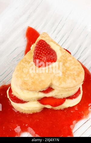 Herzförmige Erdbeeren und Vanillefeuille auf Erdbeersauce. Für einen süßen Valentinstag. Mit selektivem Fokus für den Kopierraum Stockfoto