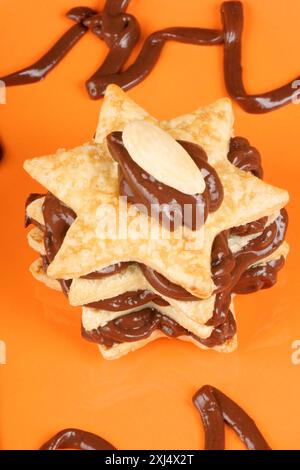 Sternförmige Schokoladencreme und Mandel-Millefeuille auf einem Orangenteller. Selektiver Fokus Stockfoto