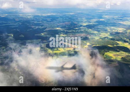 Ein Flugzeug wirft einen Schatten auf eine Wolke, Halogenregenbogen. Luftaufnahme einer Landschaft in Baden-Württemberg Stockfoto