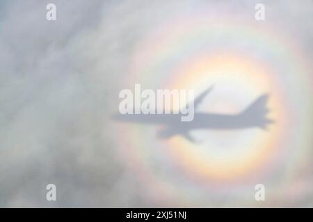 Ein Flugzeug wirft einen Schatten auf eine Wolke, Silhouette, einen Regenbogen. Deutschland Stockfoto