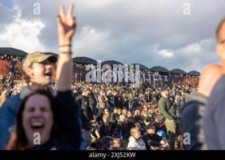 Kopenhagen, Dänemark - 19. Juni 2024: Festivalbesucher vor dem Logo beim Copenhell Metal Festival auf dem Kloverparken Camping Kopenhagen, Dänemark. Stockfoto