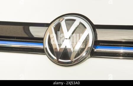 Glänzendes, silbernes Logo der Volkswagen-Firma, Emblem mit Chromeffekt auf schwarz-weißem Hintergrund mit blauem Streifen, der für eine elektrische Marke steht Stockfoto