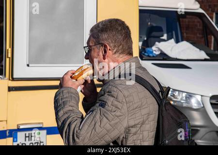 Mann isst Fischbrötchen oder Fischburger auf dem Fischmarkt im Hamburger Stadtteil Altona Stockfoto