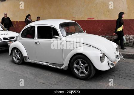 San Christobal de las Casas, Mexiko, Mittelamerika, klassisches Modell des weißen VW-Käfers auf einer belebten Straße, Leute im Hintergrund Stockfoto