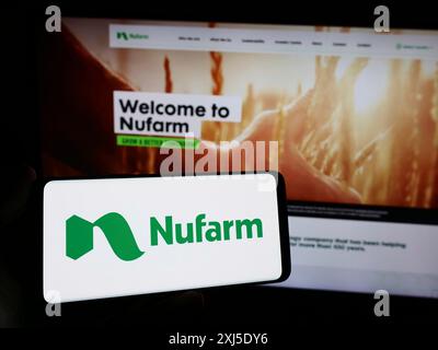 Stuttgart, Deutschland, 02.12.2024: Person, die ein Smartphone mit dem Logo des australischen Agrarchemieunternehmens Nufarm Limited vor der Website hält. Konzentrieren Sie sich auf Stockfoto