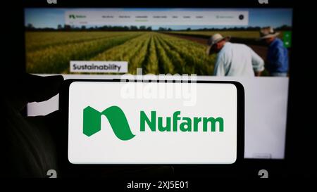 Stuttgart, Deutschland, 02.12.2024: Person, die ein Mobiltelefon mit dem Logo des australischen Agrochemieunternehmens Nufarm Limited vor der Webseite hält. Stockfoto