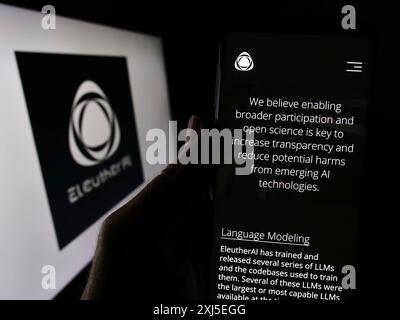 Stuttgart, 16.02.2024: Handybesitzer mit Webseite der Forschungsgruppe EleutherAI vor Logo. Konzentrieren Sie sich auf Stockfoto