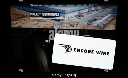 Stuttgart, Deutschland, 22.02.2024: Person, die ein Smartphone mit dem Logo des US-amerikanischen Kabelherstellers Encore Wire Corporation vor der Website hält. Stockfoto