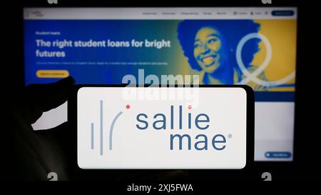 Stuttgart, Deutschland, 23.02.2024: Person, die ein Smartphone mit dem Logo der US-amerikanischen Finanzgesellschaft SLM Corporation (Sallie Mae) vor der Website hält. Fokus Stockfoto