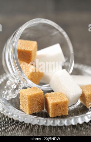 Braune und weiße Zuckerklumpen in einem Glasbecher Stockfoto