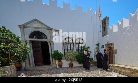 Drei Personen in einem Innenhof mit weißen Wänden und architektonischen Details, Zoodochou Pigis Kloster, die Quellen des Lebens, Chora, Patmos, Dodekanese Stockfoto