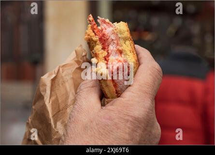 Männliche Hand, die einen Fleischkuchen und Chirozo mit einem braunen Papierbeutel hält Stockfoto