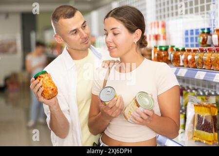 Ein Paar Mann und eine Frau, die sich für Konserven entscheiden Stockfoto