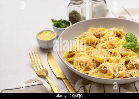 Teller mit gekochten Klößchen mit Käse und Basilikum auf weißem Hintergrund Stockfoto