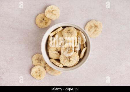 Schüssel mit leckeren gefriergetrockneten Bananen auf hellem Hintergrund Stockfoto