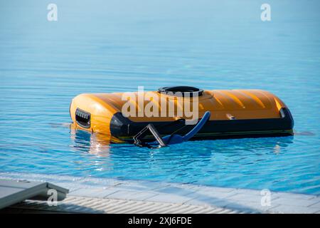 Ein hochmoderner automatisierter Poolreiniger schwimmt auf der Oberfläche eines klar blauen Schwimmbades und spiegelt die neueste Technik der Wartung von Heimbädern wider Stockfoto