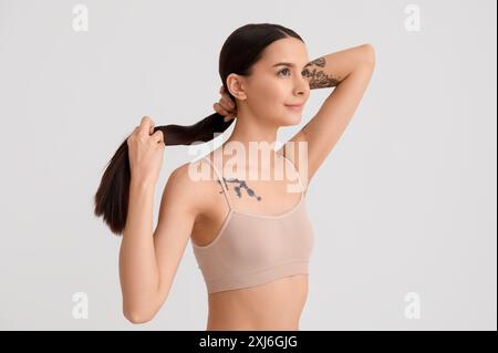 Schöne junge Frau mit langen braunen, glatten Haaren auf weißem Hintergrund Stockfoto