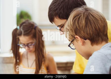 Drei Geschwister mit Brille stehen zu Hause nebeneinander und blicken auf ein Studienprojekt Stockfoto