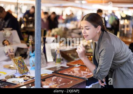 Glückliches Touristenmädchen, das Schmuck anschaut, der auf dem Flohmarkt verkauft wurde Stockfoto