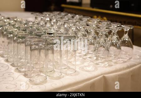 Nahaufnahme von Reihen von umgedrehten Highball- und Weingläsern auf einem Tisch bei einer Party Stockfoto