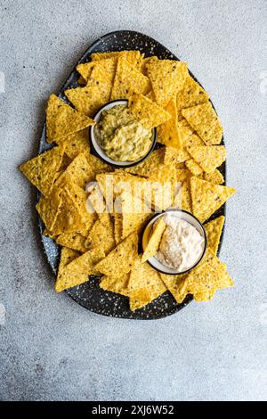 Blick von oben auf einen Teller Tortilla-Chips mit hausgemachter Guacamole und Sauerrahm-Dip Stockfoto